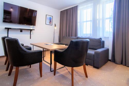 een woonkamer met een tafel en stoelen en een bank bij Warsaw Apartments - Apartamenty Sadyba in Warschau