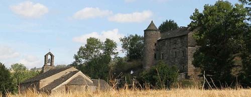 an old stone building with a tower and a church at Chambres d'hotes La Combette in Le Bleymard