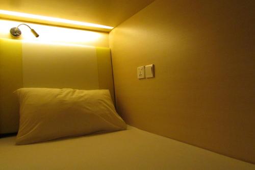1 cama con almohada blanca y una luz en la pared en The Bohemian en Singapur