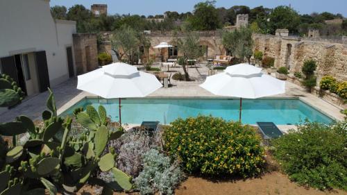una piscina con 2 sombrillas y un patio en Masseria Bernardini Art Resort, en Nardò
