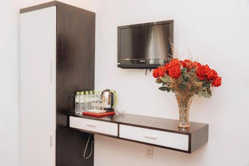 a vase filled with red roses sitting on a counter at Sunna Hotel in Da Nang