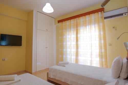a bedroom with a bed and a tv and a window at Sunny Holiday in Sarandë
