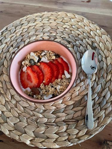 a bowl of granola with strawberries and a spoon at Bed and Breakfast De Beekhoek in Glane