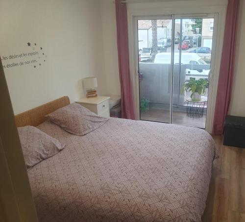 une chambre avec un lit et une porte coulissante en verre dans l'établissement l'Eldorado palavas-les-flôts, à Palavas-les-Flots
