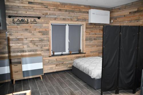 a bedroom with a bed and a wooden wall at Logement in wood (400 mètres de Pairi Daiza) in Bolignies