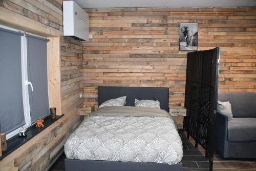 a bedroom with a bed and a wooden wall at Logement in wood (400 mètres de Pairi Daiza) in Bolignies