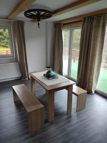 stół i ławka w pokoju z oknami w obiekcie Gościniec Śliwkula w mieście Jaworzynka