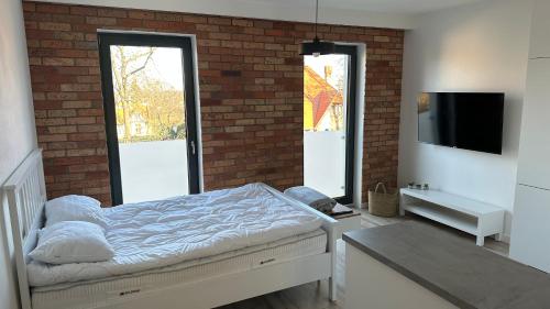 a bedroom with a bed and a brick wall at Apartamenty Mickiewicza40 in Śrem