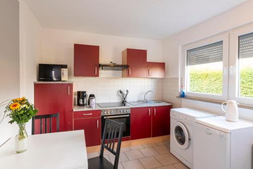 een keuken met rode kasten en een wasmachine bij Appartement-Marienrode in Hildesheim