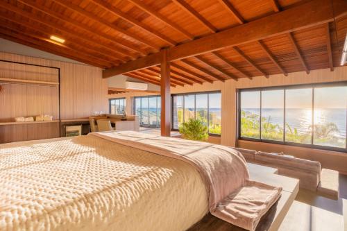 a bedroom with a large bed and large windows at Pousada Rêmora in Praia do Rosa