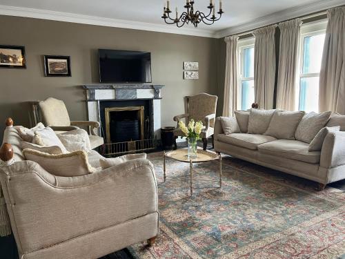sala de estar con 2 sofás y chimenea en Luxurious Converted Old Victorian Bank Building en Stewartstown