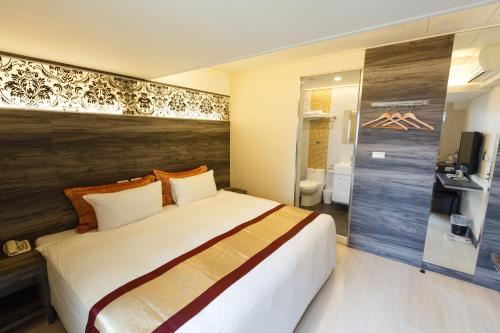 a hotel room with a large bed and a bathroom at Wecan Hotel in Kaohsiung
