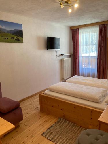 a bedroom with a bed and a tv on the wall at Schneiderhof, Urlaub auf dem Bauernhof in Ridanna