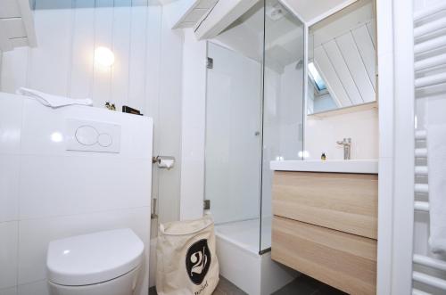 La salle de bains blanche est pourvue d'une douche et de toilettes. dans l'établissement Appartement Bellevue - centre ville, à Chamonix-Mont-Blanc