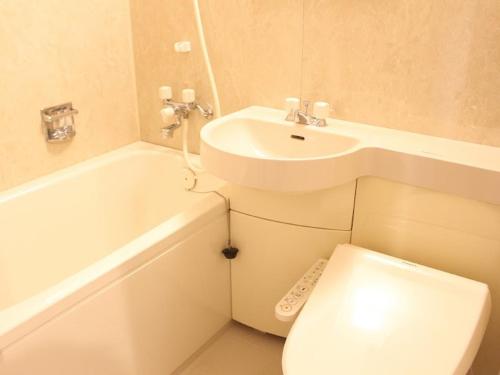 a white bathroom with a sink and a toilet at HOTEL LiVEMAX BUDGET Chiba Mihama in Chiba