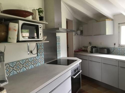 une cuisine avec des armoires blanches et un micro-ondes dans l'établissement Très belle villa avec piscine au calme de la forêt, à Le Porge