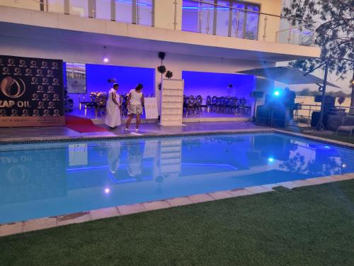 two people walking by a swimming pool at night at Botle Ba Afrika Lodge in Vereeniging