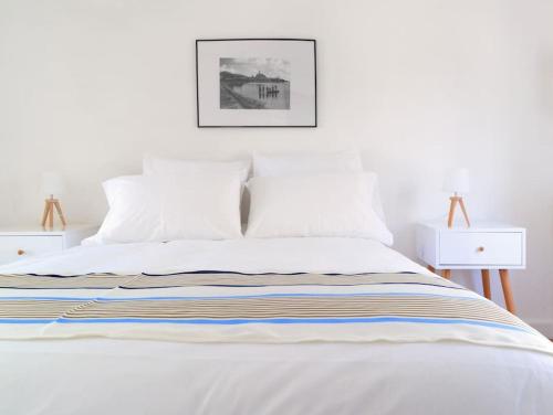 uma cama branca com lençóis brancos e uma imagem na parede em Chalet Alaric & Jacuzzi Ilot 1 rang1! VUE MER! 4rooms! CLIM 10p 24H24 em Gruissan