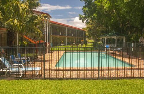 a swimming pool behind a fence with chairs and a playground at Coomera Motor Inn in Gold Coast