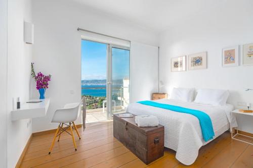 a white bedroom with a bed and a large window at Villa Thalia Floating Heaven in Porto Heli