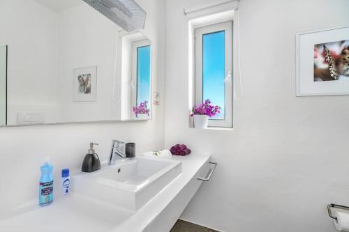 a white bathroom with a sink and two windows at Villa Thalia Floating Heaven in Porto Heli