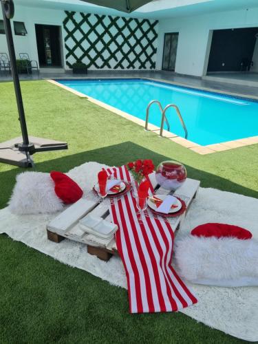 a red and white picnic table next to a pool at Botle Ba Afrika Lodge in Vereeniging