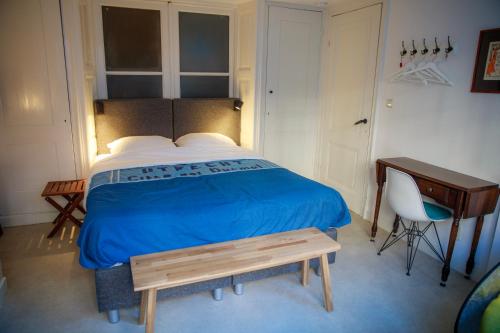 a bedroom with a bed with a blue blanket and a desk at Obrecht Welcome in Utrecht