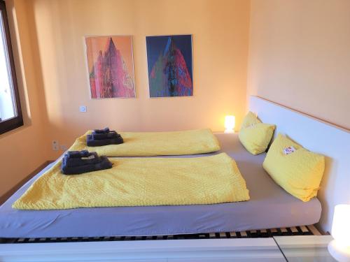 two beds in a room with yellow sheets at Vista dolce - Wohnung mit fabelhaftem Blick über die Dächer von Brissago in Brissago