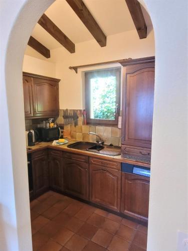 a kitchen with wooden cabinets and a window at Vista dolce - Wohnung mit fabelhaftem Blick über die Dächer von Brissago in Brissago
