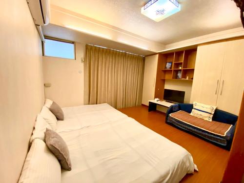a bedroom with a large white bed and a couch at Fengjia Pig's House in Taichung