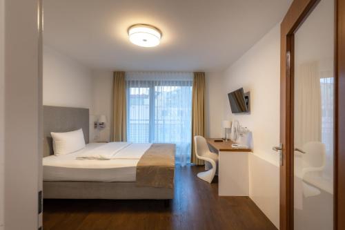 Schlafzimmer mit einem Bett, einem Schreibtisch und einem Fenster in der Unterkunft Downtown Vi Vadi Hotel in München