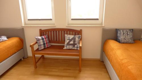 a room with two beds and a wooden chair with pillows at Haus TimpeTe am Breetzer Bodden in Vieregge