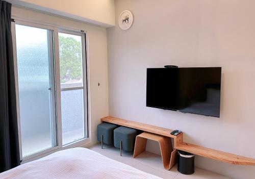 a bedroom with a flat screen tv on a wall at Happy Fat B&B 寵物友善 in Taitung City