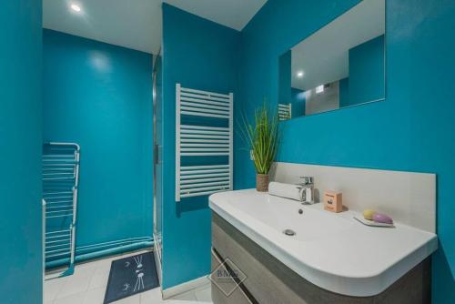La salle de bains bleue est pourvue d'un lavabo et d'un miroir. dans l'établissement Disney House, à Chessy