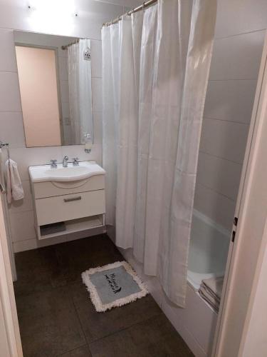 baño con cortina de ducha blanca y lavamanos en UNICO STUDIO en Buenos Aires
