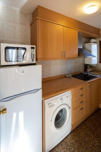 a kitchen with a washing machine and a microwave at Cal Xesc in Castellar de NʼHug