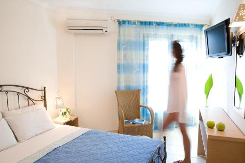 a woman standing on a bed in a bedroom at Anemolia Apartments in Vasiliki