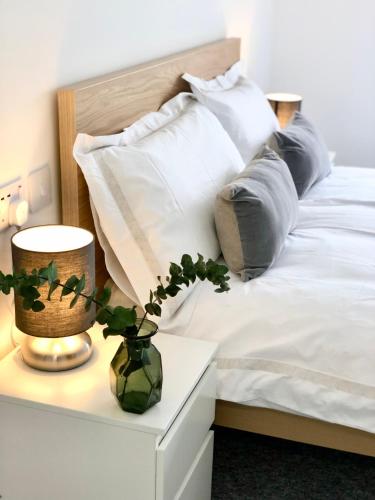 a bed with white sheets and pillows and a vase on a table at Spacious En-suite Private Double Bedroom in Oxford