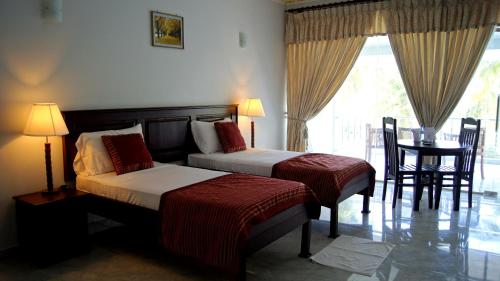 a hotel room with two beds and a table and chairs at Sea Lotus Park in Trincomalee