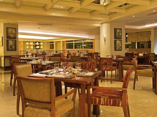 a dining room with wooden tables and chairs at Novotel Semarang in Semarang