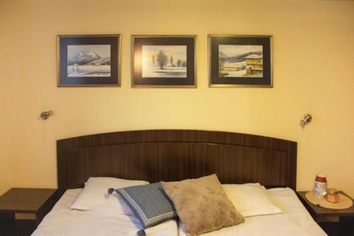 a bedroom with a bed with four pictures on the wall at Meteor Family Hotel in Chepelare