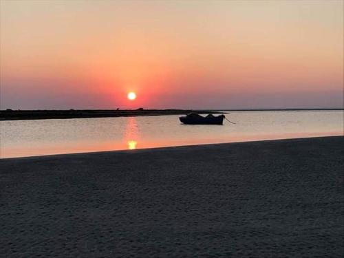 un bateau sur l'eau avec le coucher du soleil en arrière-plan dans l'établissement Belle appartement vue de mer, à Zarzis