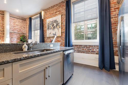 a kitchen with a sink and a brick wall at The Stella in New Orleans