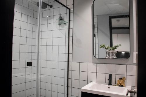 a white tiled bathroom with a sink and a mirror at Onyx Studio Apartment in Cape Town