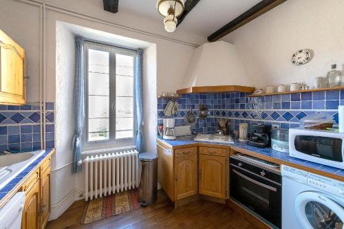 a kitchen with blue tiles on the walls and a window at Le Clos d'Albray - Chambres d'hôtes et gite in Comps-la-Grand-Ville