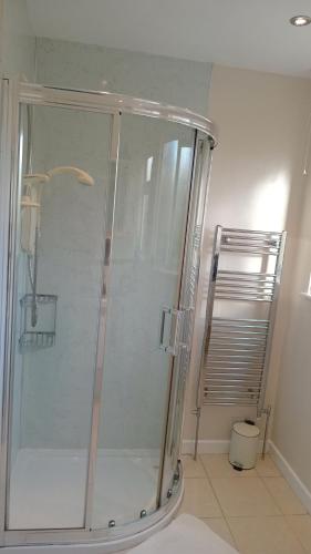 a shower with a glass door in a bathroom at Curlews Cottage - House with 3 bedrooms and garden - walking distance to the beach in Perranporth