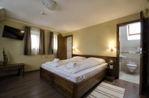 a bedroom with a large bed and a bathroom at Bocor Fogadó in Kisharsány