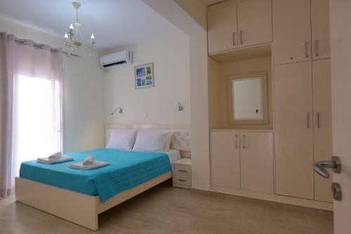 a bedroom with a bed with blue sheets and a window at Sunny Holiday in Sarandë