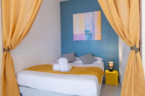 - une chambre dotée d'un lit avec des murs et des rideaux bleus dans l'établissement Cosy Studio près des Palaces Mentonnais, à Menton