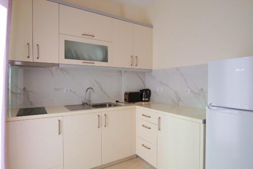a white kitchen with a sink and a microwave at Sunny Holiday in Sarandë